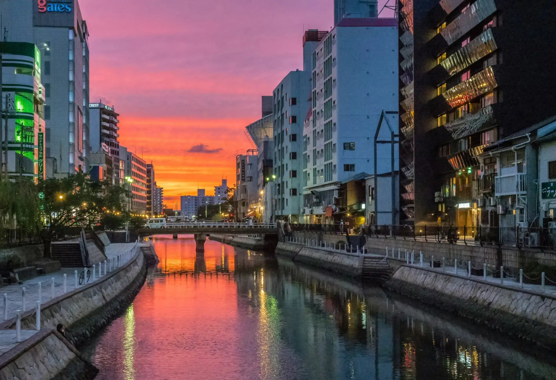 A view of Fukuoka city with modern buildings along the waterfront at sunset.