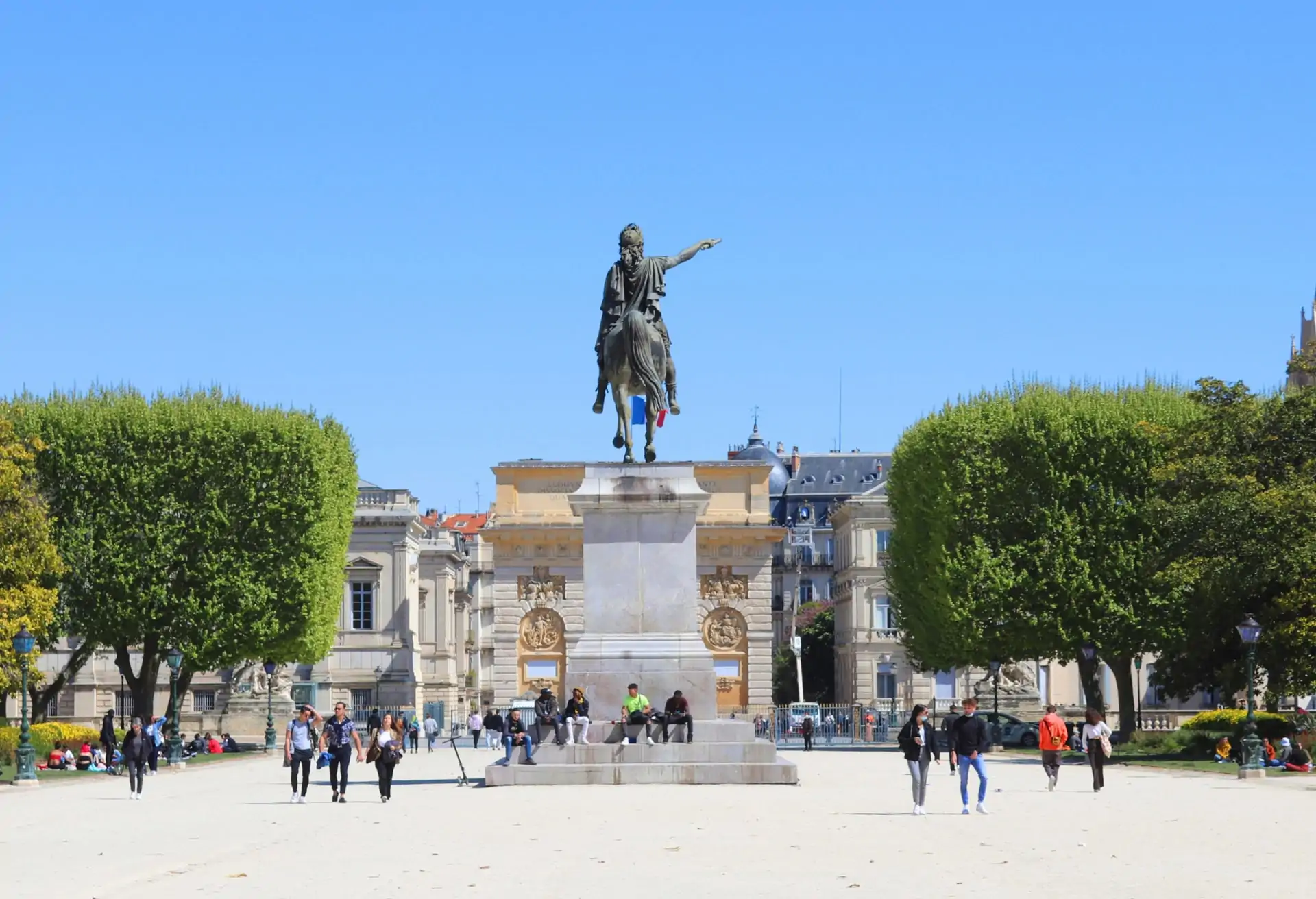 A statue of Louis XIV on a horse with buildings and trees below.