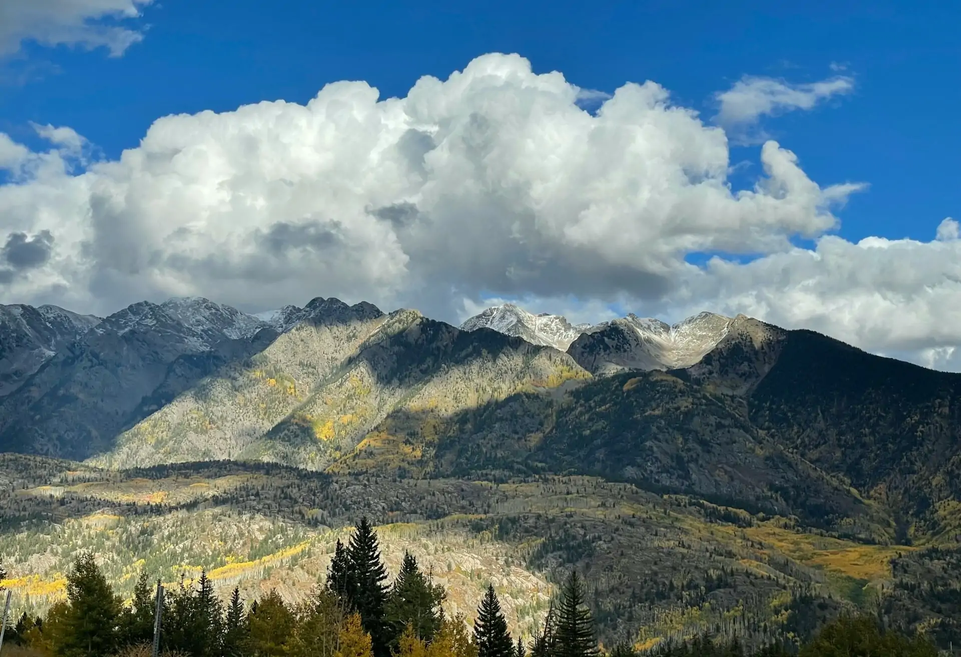 A view of Durango's mountain range with grey and green mountains under a cloudy sky.