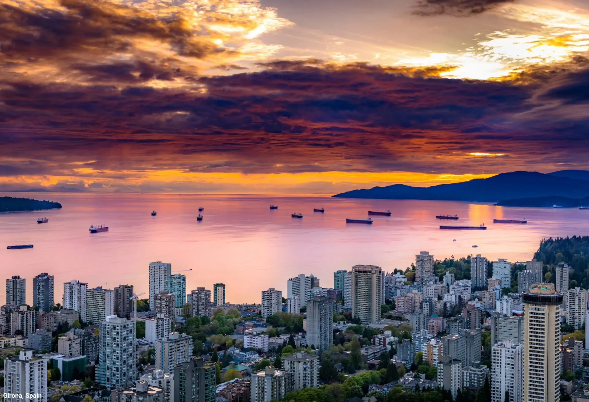 A view of a vast lake at sunset with modern buildings in the foreground.