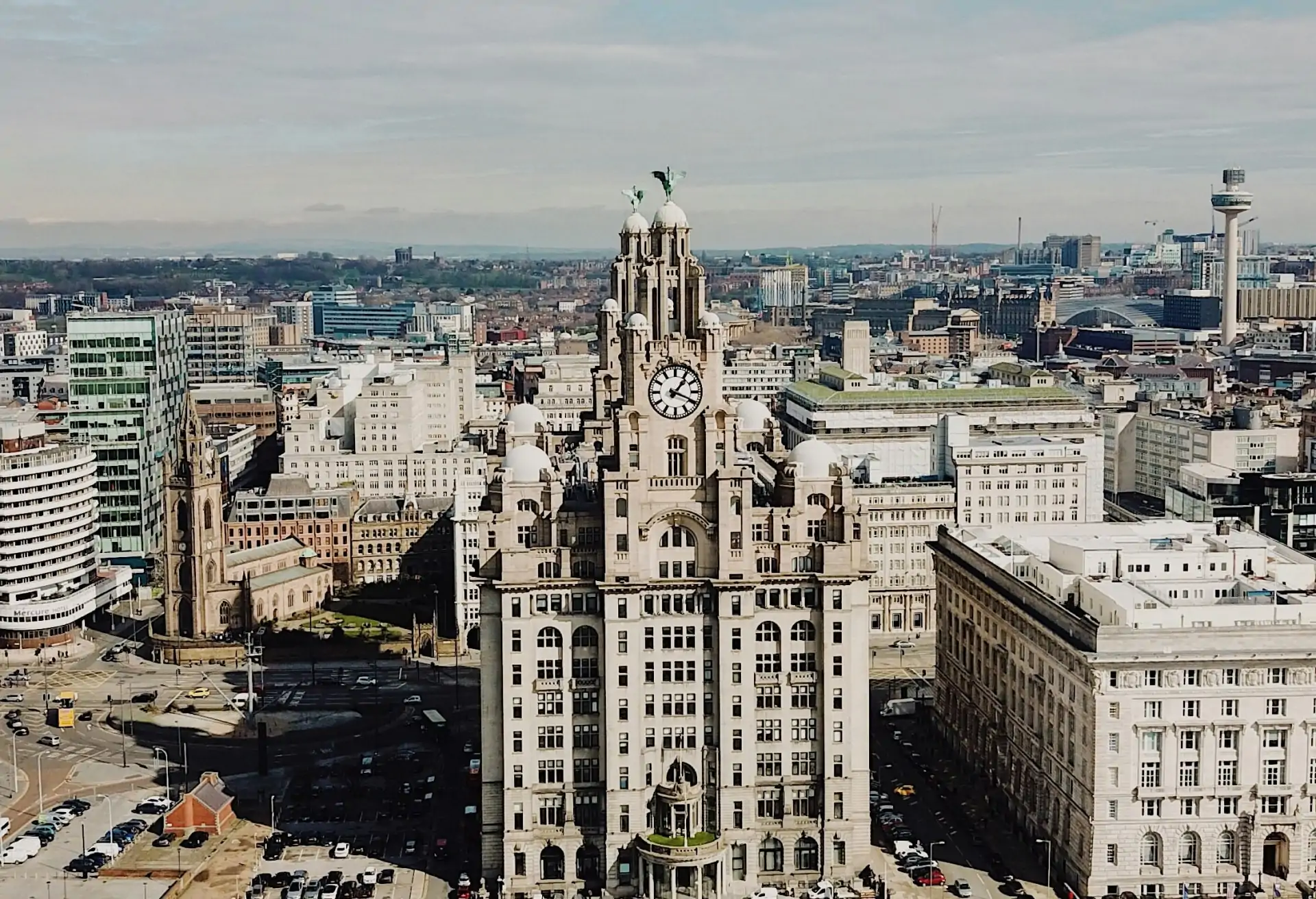 A view of Liverpool’s historic Royal Liver Building featuring the clocktower and modern buildings in the background.