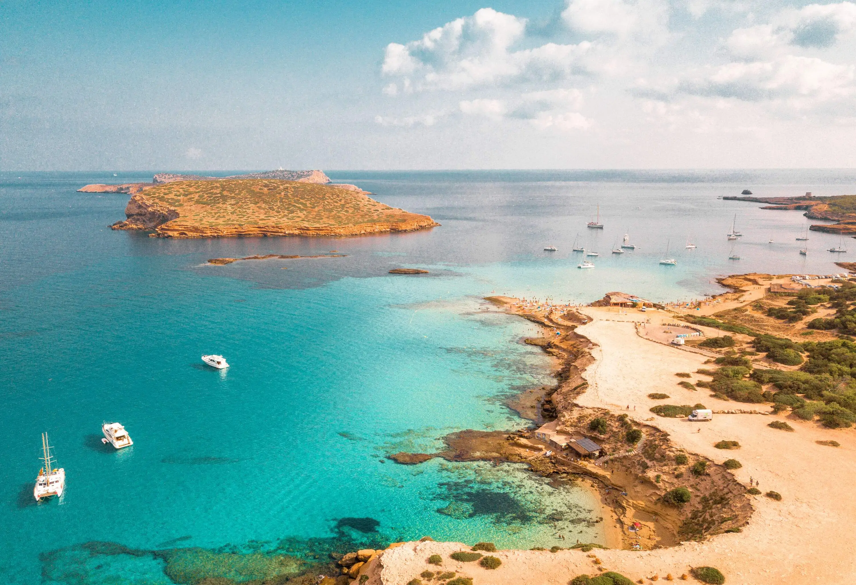 Small boats docked over crystal clear waters alongside a shore.