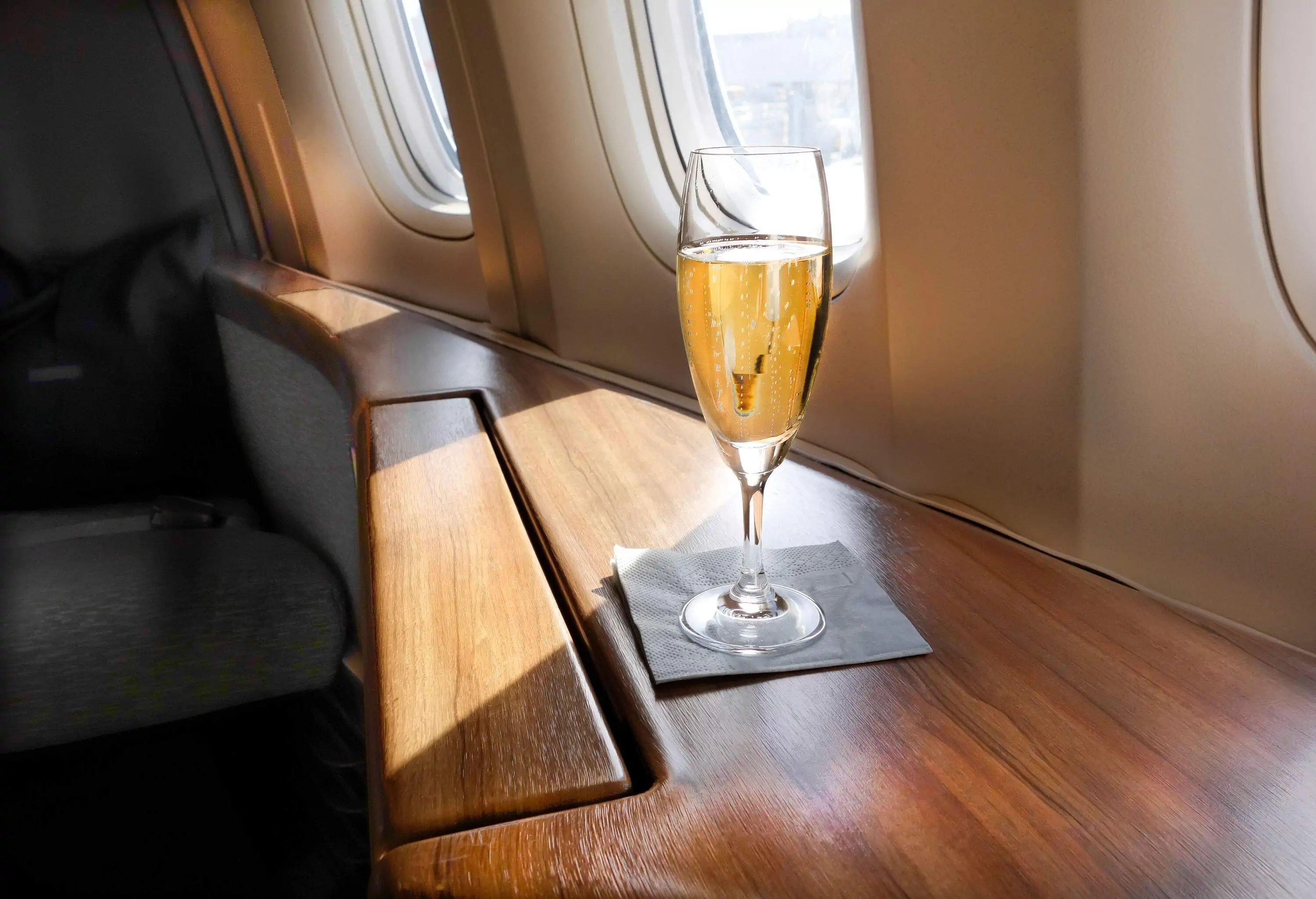 A glass of exquisite champagne awaits a privileged first-class passenger, ready to be savoured during their luxurious airline journey.