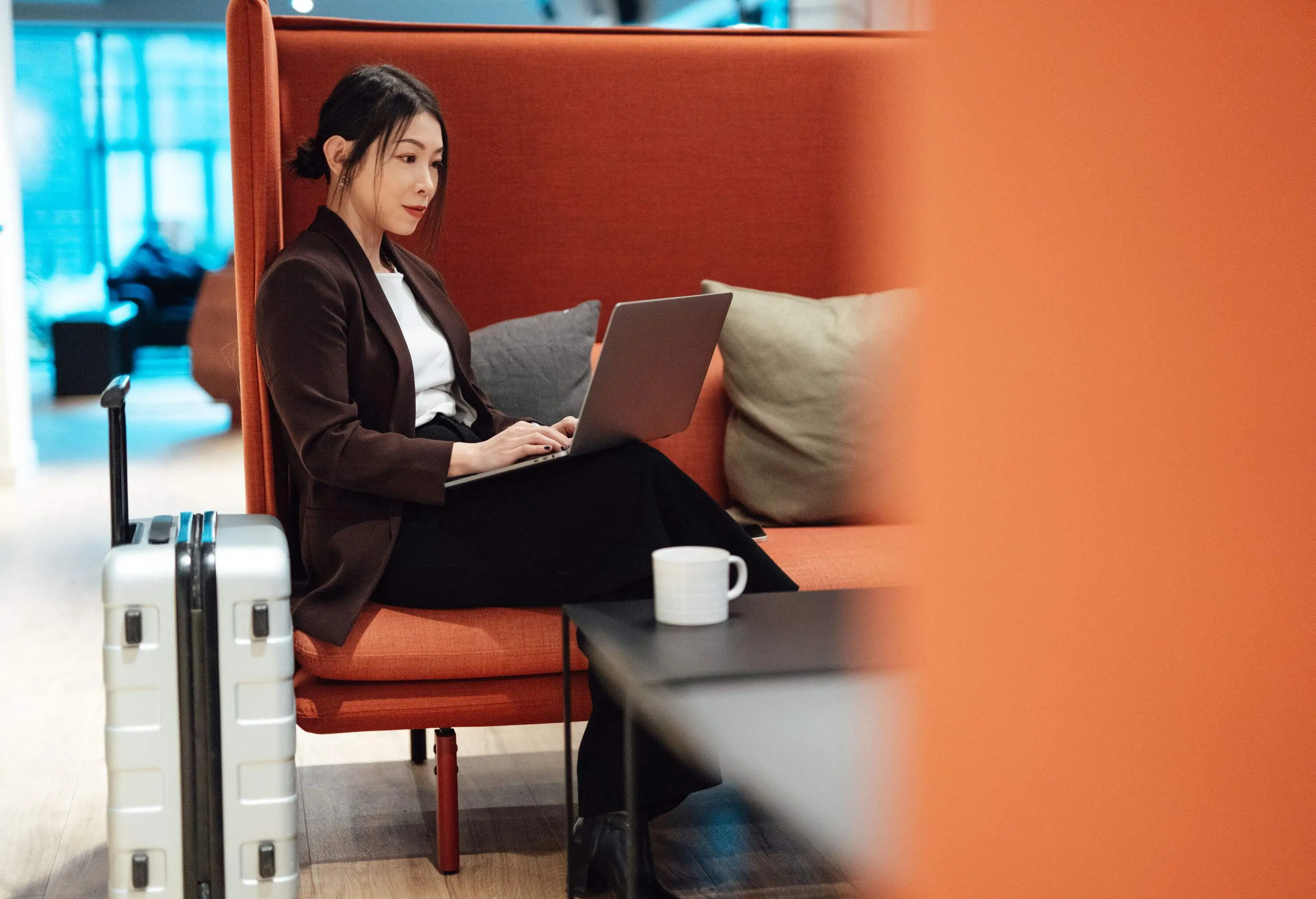 Business woman checking emails with laptop while sitting at airport lounge, getting ready to depart. Young woman on business trip.